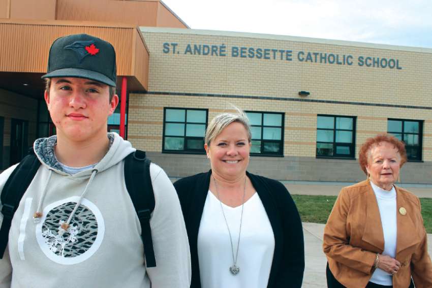 Noah Ethier, his mother Michelle Ethier and grandmother Simone Bessette stand outside the new Fort Saskatchewan school named after their relative, St. André Bessette. 