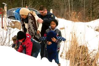 A woman and her family from Sudan is taken into custody by a Royal Canadian Mounted Police officer after arriving Feb.12 by taxi and walking across the U.S.-Canada border into Quebec.
