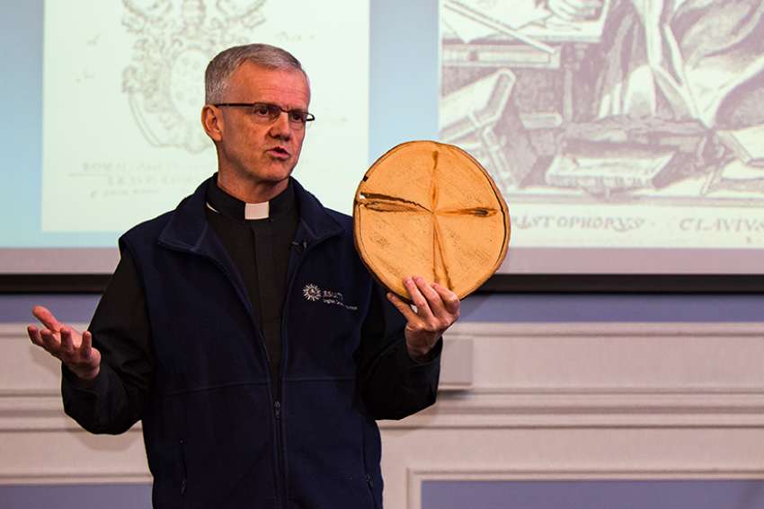 Fr. John McCarthy, in his lecture at Regis College March 21, displays a tree core sample he found in New Brunswick that handily demonstrates the Jesuit principle of finding God in all things. McCarthy is a lichenologist and ecologist who also is chaplain at the University of British Columbia. 