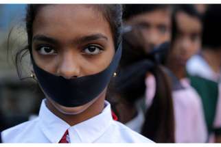 A student tapes her mouth shut during a March 16 candlelight vigil for an elderly nun who was raped in Ranaghat, India. 