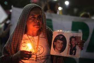 A woman holding a candle and images of disappeared victims takes part in a rally for peace Oct. 7 in Medellin, Colombia. Colombia&#039;s Catholic bishops urged the government and armed rebels to commit to an indefinite cease-fire while a new peace deal is negotiated.