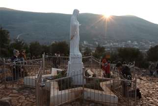 Pilgrims pray around a statue of Mary on Apparition Hill in Medjugorje, Bosnia-Herzegovina, in this 2011 file photo.