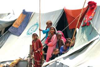 Children displaced by flooding stand outside their family tent while waiting for food handouts and relief material in Sehwan, Pakistan, Sept. 14.