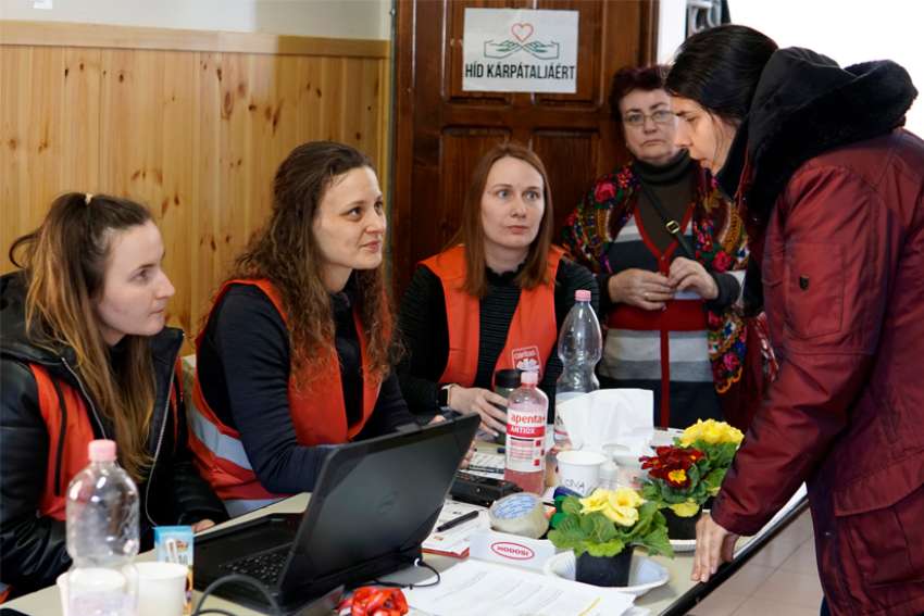 Caritas volunteers assist a Ukrainian refugee at the Caritas Hungary refugee center in Barabás, Hungary, March 10, 2022. More than 214,000 Ukrainians have fled to Hungary, according to a March 8 statistic from the U.N. Refugee Agency.