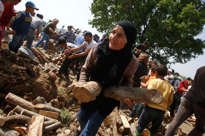A woman holds firewood distributed near a makeshift camp for migrants April 14 at the Greek-Macedonian border near the village of Idomeni, Greece. A Vatican spokesman said Pope Francis&#039; April 16 trip to Greece is humanitarian, not political.
