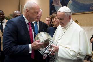 Pope Francis is presented with an American football helmet during a meeting with members of American Pro Football Hall of Fame June 2017 at the Vatican. 