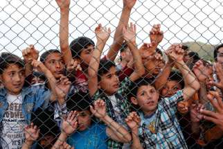  Syrian children stand at a fence April 23 at a refugee camp near Gaziantep, Turkey. Pope Francis told diplomats to the Holy See to not fear helping migrants who are in need.