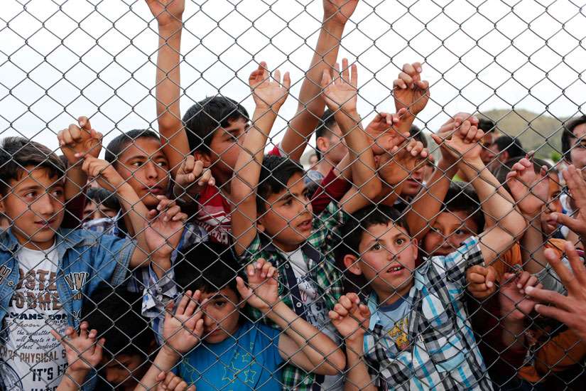  Syrian children stand at a fence April 23 at a refugee camp near Gaziantep, Turkey. Pope Francis told diplomats to the Holy See to not fear helping migrants who are in need.