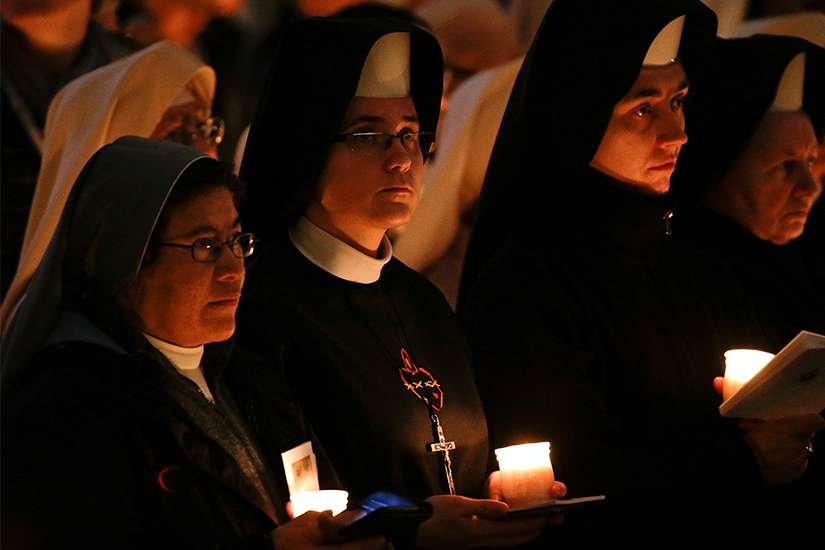 Women religious hold candles as they wait for Pope Francis to arrive for Mass with consecrated women and men marking the feast of the Presentation of the Lord in St. Peter&#039;s Basilica at the Vatican Feb. 2.