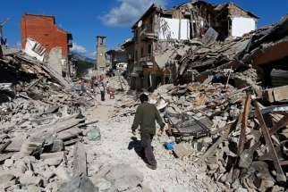 A man walks amidst rubble following an earthquake in Pescara del Tronto, central Italy, August 24, 2016. 
