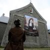 A woman looks at a banner of St. Kateri Tekakwitha displayed outside St. Francis Xavier Church, where she is buried, in Kahnawake, Quebec, Oct. 21. Pope Benedict XVI created seven new saints that day, including St. Kateri, a 16th-century Mohawk-Algonquin woman known as the &quot;Lily of the Mohawks.&quot; 