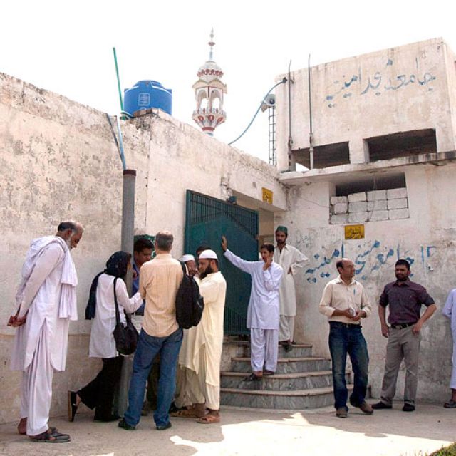 Members of the media and residents gather outside a mosque Aug. 23 near the locked family house of Rimsha Masih, a Pakistani Christian girl accused of blasphemy, on the outskirts of Islamabad.