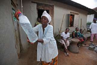 To curb the spread of Ebola, a Liberian woman washes her hands using a bottle of chlorine water in Jene Wonde, a village near the border with Sierra Leone, Nov. 9. Catholic Relief Services committed $1.5 million to its pre-existing programs in Sierra Leo ne, Liberia and Guinea, the three West African countries affected by widespread transmission of the Ebola virus. The money is being used a number of ways, including to train heath workers, ensure safe and dignified burials, and maintain local Catholic-run health care facilities. 