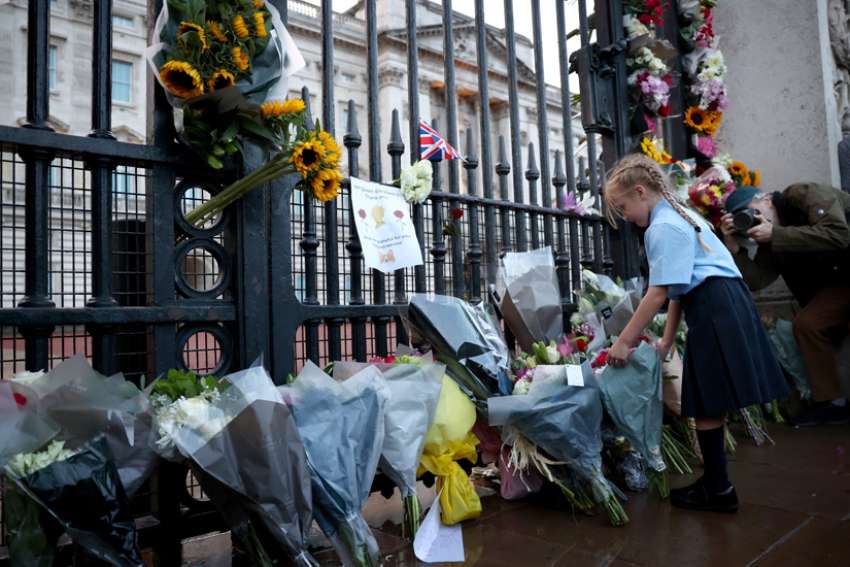 A girl places flowers outside Buckingham Palace in London Sept. 8, 2022, after Queen Elizabeth II -- Britain&#039;s longest-reigning monarch and the nation&#039;s figurehead for seven decades -- died at the age of 96.