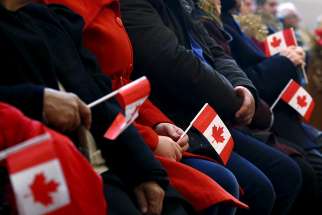 Syrian refugees hold Canadian flags as they take part in a welcome service in 2015 at a church in Toronto. 