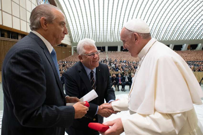 Pope Francis greets Dr. Ramon Tallaj, founder and chairman of the board of Somos Community Care, and Mario J. Paredes, chief executive officer, during a Sept. 20, 2019, symposium at the Vatican on the health care needs of immigrants.