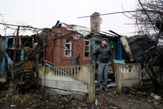  A man stands in front his damaged house after shelling March 24 in the Ukrainian town of Makeevka.