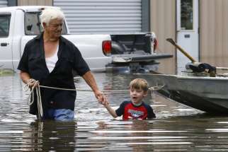Richard Rossi and his 4-year-old great-grandson Justice wade through water Aug. 15 after their home flooded in St. Amant, La.