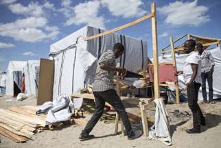 Sudanese men build a structure to house them in the &quot;Jungle&quot; migrant camp near Calais, France, Aug. 5. Catholic bishops from France and Britain have urged their governments to settle a growing refugee crisis around the port of Calais, where highways have been blocked and migrants from Africa and the Middle East have died attempting illegal crossings of the Channel Tunnel. 