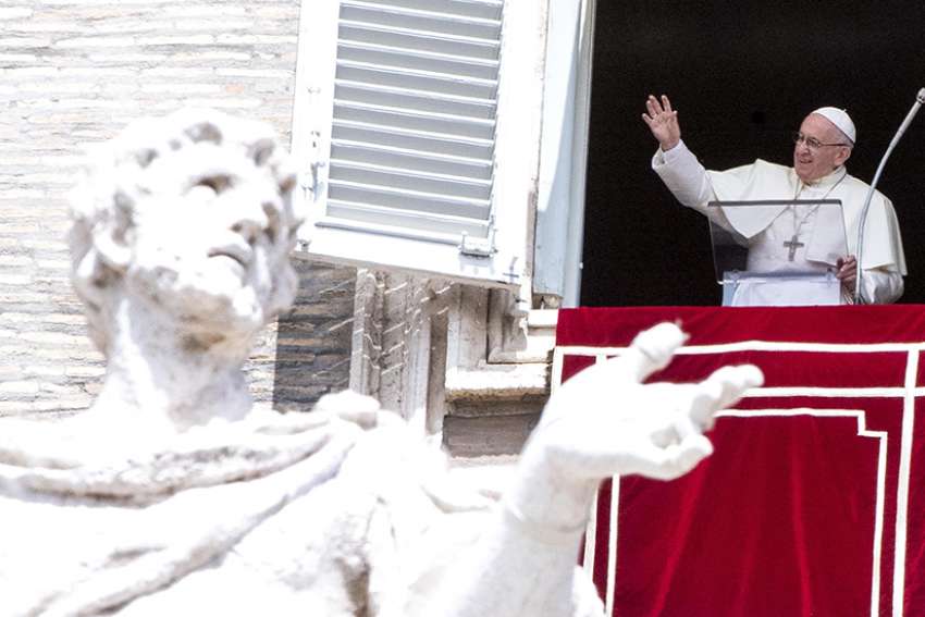 Pope Francis waves as he leads the Angelus from the window of his studio overlooking St. Peter&#039;s Square at the Vatican Aug. 15, the feast of the Assumption.