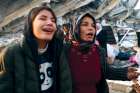 Earthquake survivors react while standing amid destroyed buildings in Hatay, Turkey. A powerful 7.8 magnitude earthquake rocked areas of Turkey and Syria early Feb. 6, toppling hundreds of buildings and killing thousands.