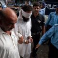 Police escort blindfolded man after being arrested on suspicion of framing Pakistani Christian girl