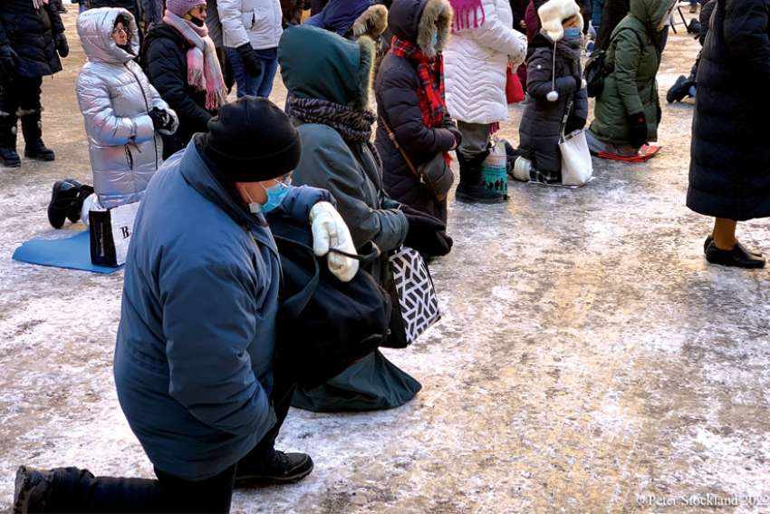 Parishioners taking part in an outdoor Mass kneel on the frozen ground of the parking lot at Mary, Queen of the World Cathedral in Montreal.