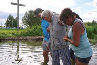 Mary Agnes Herman is helped out of Lac Ste. Anne after walking 429 kilometres to the pilgrimage site. 