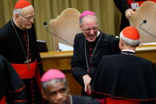 Archbishop Paul-Andre Durocher, president of the Canadian Conference of Catholic Bishops, laughs as he talks with Cardinal Donald W. Wuerl of Washington before the morning session of the extraordinary Synod of Bishops on the family at the Vatican Oct. 9. At left is Cardinal Peter Erdo of Esztergom-Budapest, Hungary, relator for the synod. 