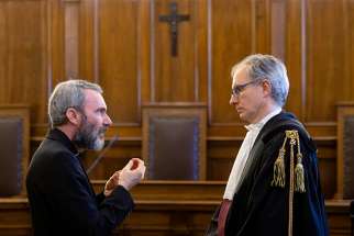 Msgr. Carlo Alberto Capella, left, a former Vatican diplomat who served in Washington, talks to his lawyer during his sentencing in a Vatican court June 23. Msgr. Capella was found guilty of possessing and distributing child pornography and sentenced to five years in a Vatican prison and fined 5,000 Euro. 
