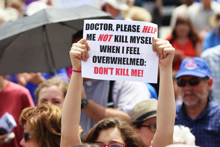 A woman holds up a sign during a rally against assisted suicide in 2016 on Parliament Hill in Ottawa, Ontario. Canada is projected to exceed assisted suicide and euthanasia deaths in the Netherlands and Belgium. 