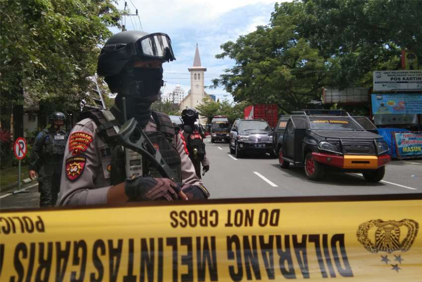 Armed police officers stand guard along a closed road following a suicide bomb attack during Palm Sunday Mass at Sacred Heart of Jesus Cathedral in Makassar, Indonesia, March 28, 2021.