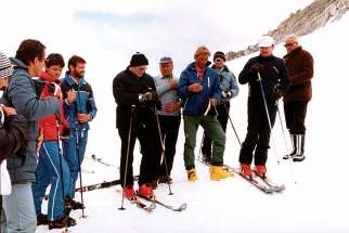 Pope John Paul II, in a black ski jacket and hat, prays with a group of skiers before heading down a slope in Italy in 1984.