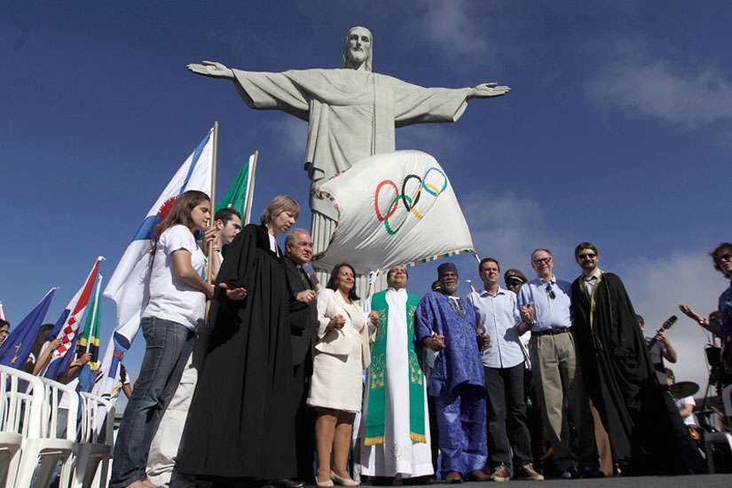 Rio de Janeiro&#039;s Mayor Eduardo Paes, in untucked dress shirt; Brazilian Olympic Committee President Carlos Arthur Nuzman, in khaki pants; and leaders of different religions pray next to the Olympic Flag in front of &quot;Christ the Redeemer&quot; statue during a blessing ceremony in Rio de Janeiro on Aug. 19, 2012