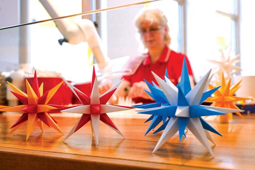An employee of the Herrnhut Star Co. in Hernnhut, Germany, creates the famous Christmas Moravian stars as visitors tour the workshop.
