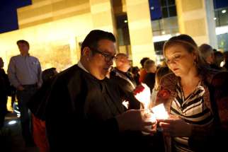 Father Manuel Cardoza, administrator at Our Lady of Hope Church in San Bernardino, Calif., and Carmella Swanson, light candles during a Dec. 7 vigil in San Bernardino in memory of the 14 victims killed in a Dec. 2 mass shooting at a social services center. The many vigils held around San Bernardino for the shooting victims included a Dec. 7 evening interfaith service at Our Lady of the Rosary Cathedral.