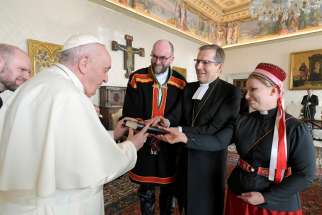 Pope Francis accepts a gift during an audience with an ecumenical delegation from Finland at the Vatican Jan. 17, 2022. Presenting the gift were Lutheran Bishop Jukka Keskitalo of Oulu, flanked by two Lutheran pastors, the Rev. Tuomo Huusko and the Rev. Mari Valjakka. The two pastors, who are wearing traditional Sámi dress, minister to the Indigenous community.