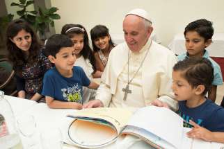 Pope Francis sits with refugee children from Syria at a luncheon at the Vatican August 11.