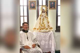 Marvin-Paul Fernandez with a statue of Mary at Assumption of the Blessed Virgin Mary Parish in Ottawa.