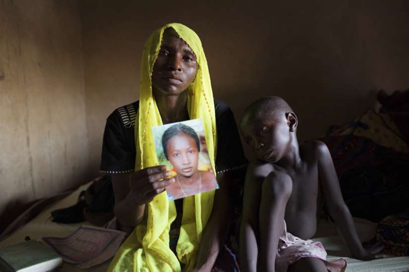 Rachel Daniel, 35, holds up a picture of her abducted daughter, Rose Daniel, 17, as her son Bukar, 7, sits beside her at her home in Maiduguri on May 21, 2014. Rose was abducted along with more than 200 of her classmates on April 14, 2014, by Boko Haram militants from a secondary school in Chibok, Borno state.