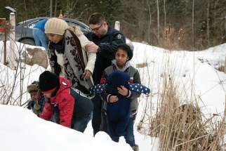 A woman is taken into custody by a Royal Canadian Mounted Police officer after arriving Feb.12 by taxi and walking across the U.S.-Canada border into Quebec last winter. More than 8,000 asylum seekers have crossed from the United States into Canada this year. 