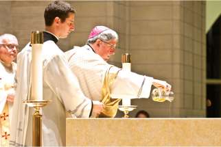 Cardinal Thomas Collins pours the chrism oil on the altar at St. Padre Pio Church in Kleinberg, Ont.