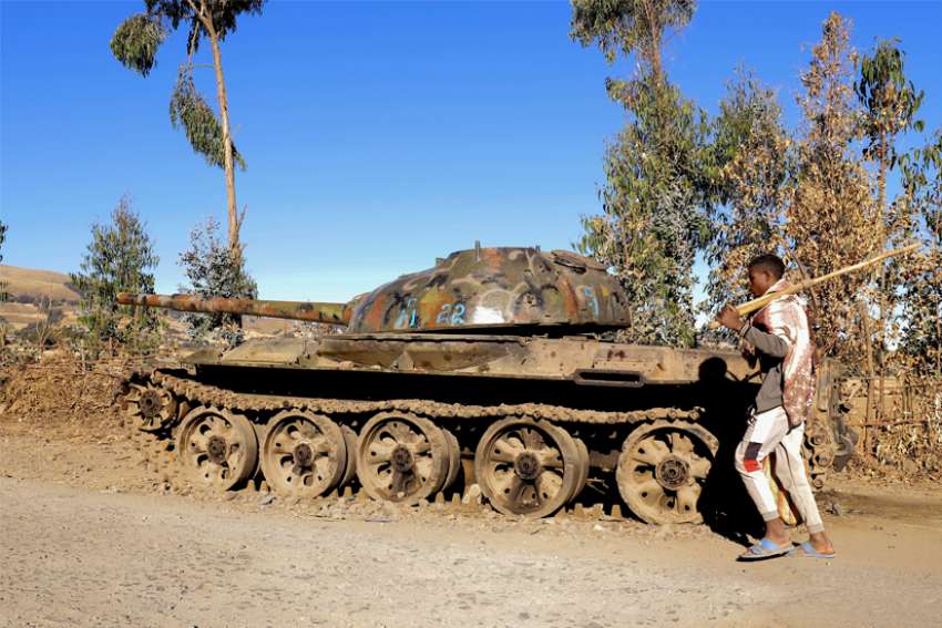 A farmer walks past an abandon military tank in Ethiopia&#039;s Tigray region Dec. 7, 2021. International human rights organizations said the regional Amhara security forces and an allied militia known as Fano were responsible for a surge in mass detentions, killings and forced expulsions of ethnic Tigrayans.