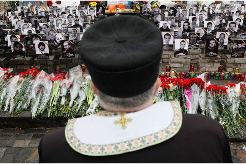 A clergyman stands near photos of people killed in Ukrainian protests in 2014, during a Feb. 20 commemorating ceremony in Kiev&#039;s Independence Square.