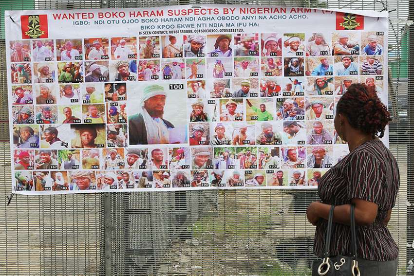 A woman in Bayelsa, Nigeria, reads a Nigerian army poster picturing wanted Boko Haram suspects May 19, 2016. 