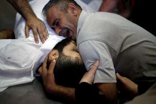 The brother of Palestinian Shaher al-Madhoon, who was killed during a protest at the Israel-Gaza border, reacts over his body May 14 at a hospital morgue in Gaza. 