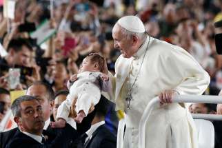 Pope Francis greets a baby as he arrives to celebrate Mass in Tokyo Dome in Tokyo Nov. 25, 2019.