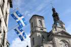 Quebec provincial flags are displayed outside a building across the street from the Cathedral-Basilica of Notre-Dame de Quebec in Quebec City Oct. 5. 