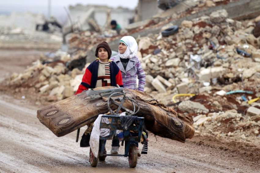 Syrian children transport their salvaged belongings from their damaged house in Doudyan, a village in northern Aleppo, Jan. 2.