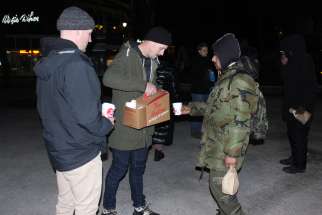 Members of the Mission St. Irenaeus parish youth group offer warm beverages to the homeless on Boxing Day, Dec 26, 2023.